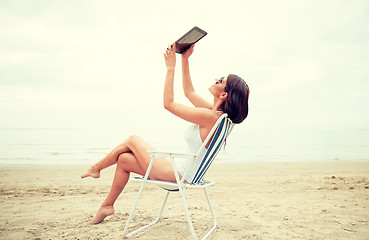Image showing happy woman with tablet pc taking selfie on beach