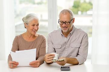 Image showing senior couple with money and calculator at home