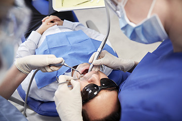 Image showing female dentist treating male patient teeth