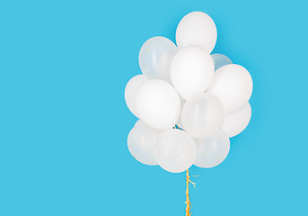 Image showing close up of white helium balloons over blue