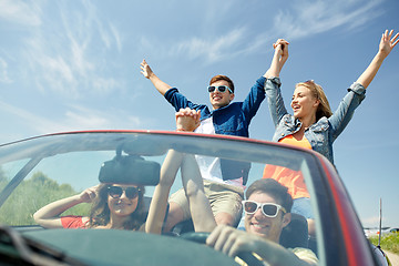 Image showing happy friends driving in cabriolet car at country