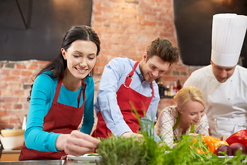 Image showing happy friends and male chef cooking in kitchen