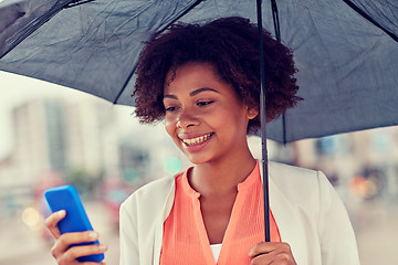 Image showing businesswoman with umbrella texting on smartphone