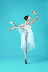 Image showing Ballerina in white dress posing on toes, studio background.