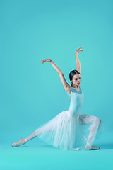 Image showing Ballerina in white dress posing on toes, studio background.