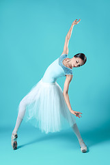 Image showing Ballerina in white dress posing on toes, studio background.