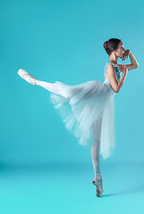 Image showing Ballerina in white dress posing on toes, studio background.