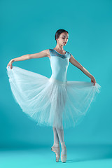 Image showing Ballerina in white dress posing on toes, studio background.