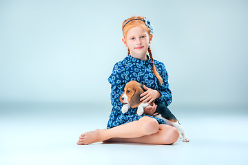 Image showing The happy girl and a beagle puppie on gray background