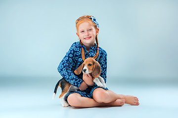 Image showing The happy girl and a beagle puppie on gray background