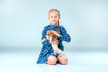 Image showing The happy girl and a beagle puppie on gray background