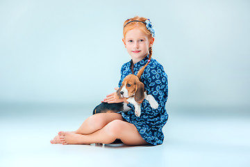 Image showing The happy girl and a beagle puppie on gray background