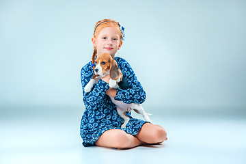 Image showing The happy girl and a beagle puppie on gray background