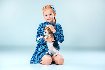 Image showing The happy girl and a beagle puppie on gray background