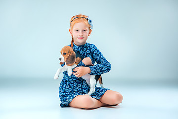 Image showing The happy girl and a beagle puppie on gray background