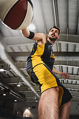 Image showing The portrait of a basketball player with ball against gray gym background