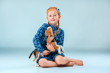 Image showing The happy girl and a beagle puppie on gray background