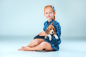 Image showing The happy girl and a beagle puppie on gray background