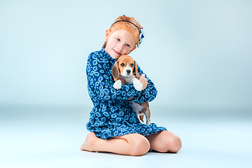 Image showing The happy girl and a beagle puppie on gray background