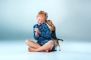 Image showing The happy girl and a beagle puppie on gray background