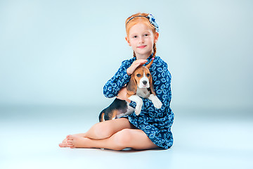 Image showing The happy girl and a beagle puppie on gray background