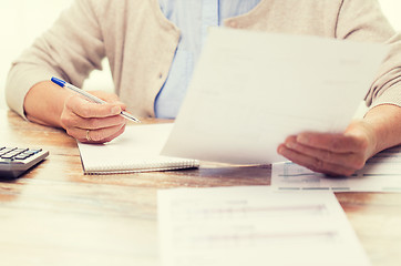 Image showing senior woman with papers and calculator at home