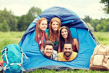 Image showing happy friends with backpacks in tent at camping