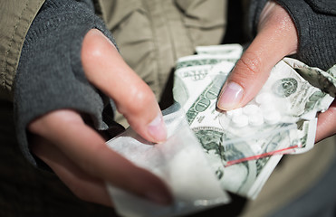 Image showing close up of addict hands with drugs and money