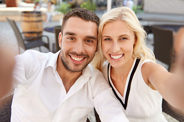 Image showing happy couple taking selfie at restaurant terrace