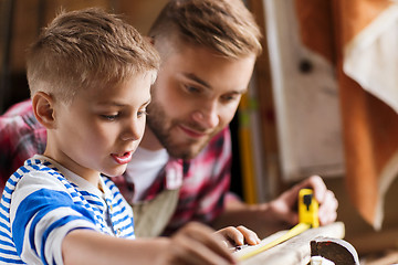 Image showing father and son with ruler measure wood at workshop