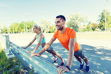 Image showing close up of happy couple doing push-ups outdoors