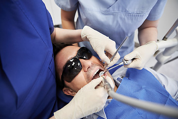 Image showing dentist hands treating male patient teeth