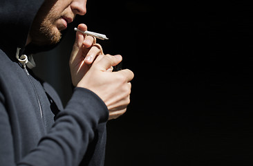 Image showing close up of addict lighting up marijuana joint