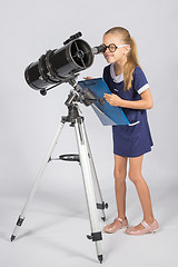 Image showing The young astronomer in glasses with interest peers into the eyepiece of the telescope