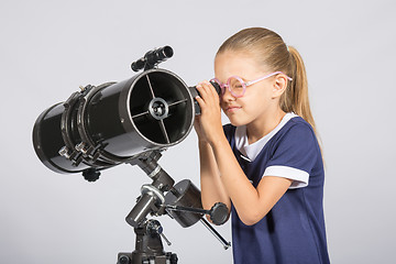 Image showing Seven-year girl in glasses with interest looks in a reflector telescope