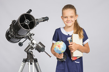 Image showing Girl astronomer is a telescope with a globe and books in the hands