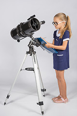 Image showing The young astronomer with glasses writes observations