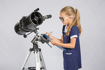 Image showing Young girl with glasses writes astronomer observations