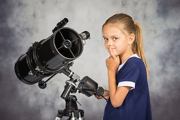 Image showing Seven-year girl thoughtfully looks in the picture, standing at the telescope