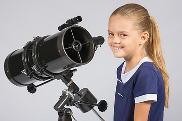 Image showing The young astronomer at the telescope is smiling and looking to the frame