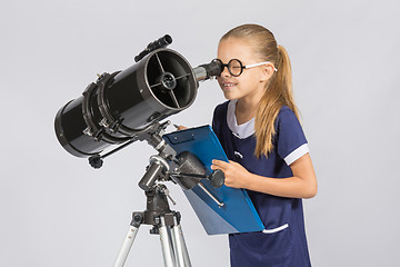 Image showing The young astronomer happy to look through the telescope recording observations