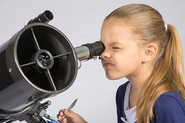 Image showing The young astronomer looks through the eyepiece of the telescope and record results