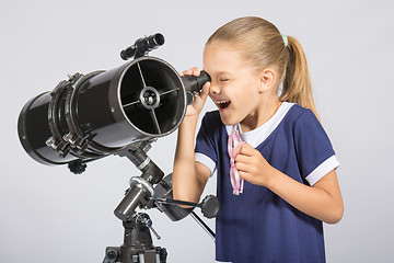 Image showing Seven-year girl with interest and mouth open looking into the reflector telescope and looks at the sky