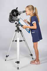 Image showing The young astronomer happy to look through the telescope recording observations