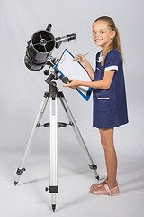 Image showing Happy girl astronomer looks happy in the picture standing next to the telescope