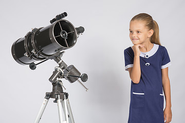 Image showing Seven-year girl with interest looking at a reflector telescope