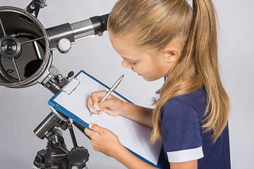 Image showing Girl astronomer writes on a sheet of paper of a starry sky with your telescope
