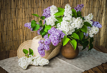 Image showing Still-life with a bouquet of lilacs and a straw hat, close-up