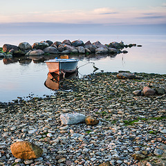 Image showing Rocky shore of the sea and fishing boat at sunset