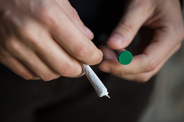 Image showing close up of addict hands with marijuana joint tube